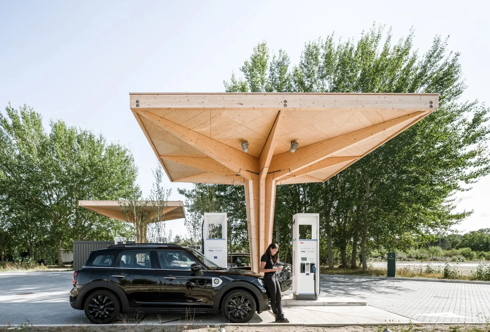Coche eléctrico en un punto de recarga público con marquesinas de madera