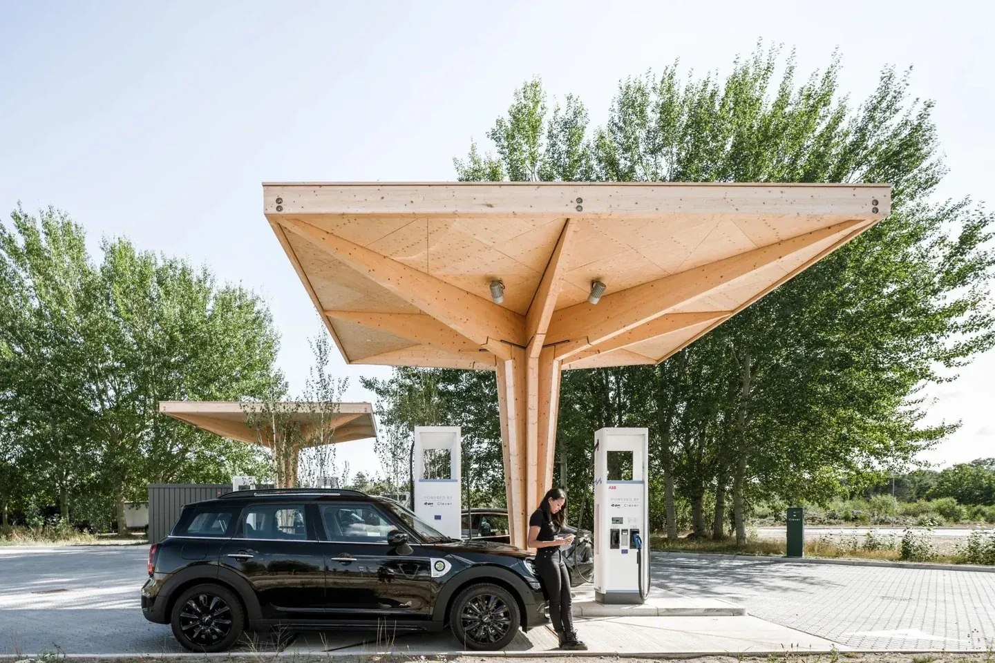 Electric car at a public charging hub with timber canopies